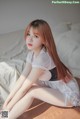 A woman sitting on a bed in a white lingerie.