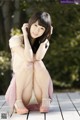 A woman in a pink dress sitting on a wooden floor.