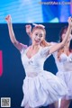 A woman in a white dress dancing on a stage.