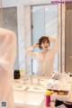 A woman standing in front of a mirror in a bathroom.