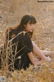 A woman sitting in a field of dry grass.