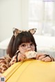 A woman wearing cat ears and glasses eating a cupcake.