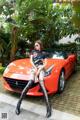 A woman sitting on top of a red sports car.