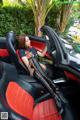 A woman sitting in the driver's seat of a red and black car.