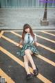 A woman in a school uniform sitting on the ground.