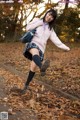 A young woman in a school uniform is jumping in the air.