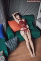 A woman in a red lingerie laying on a green couch.