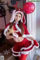 A woman dressed as a santa claus holding a red balloon.