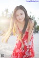 A woman in a red dress standing on a beach.