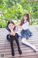 A couple of young women sitting on top of a wooden floor.