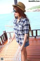 A woman wearing a hat and sunglasses standing on a dock.