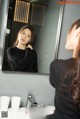 A woman standing in front of a bathroom mirror.