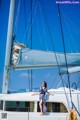 A woman standing on the deck of a sailboat.