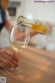 A woman pouring a glass of white wine into a wine glass.